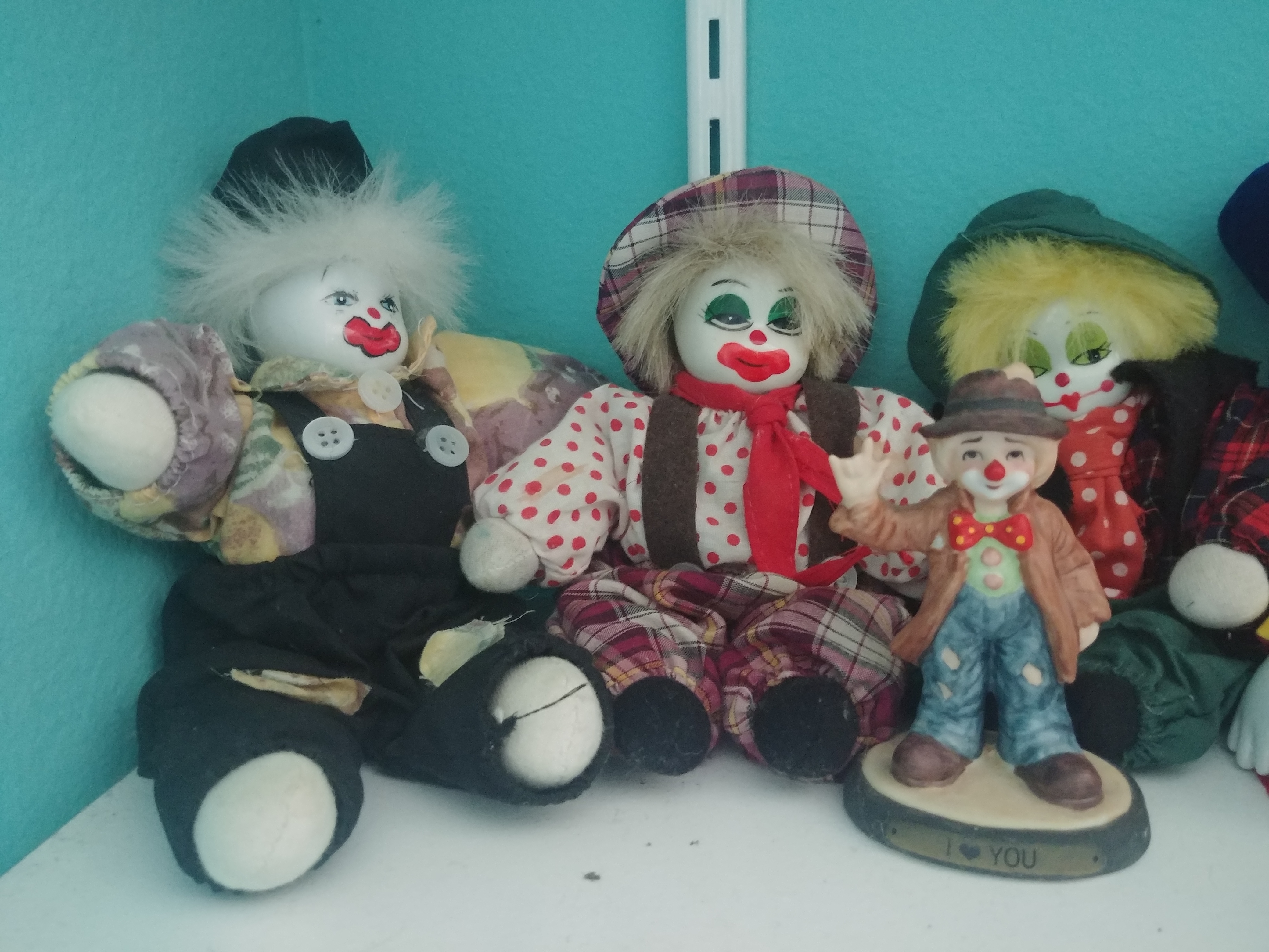 three clown dolls, a small statue of a clown in front